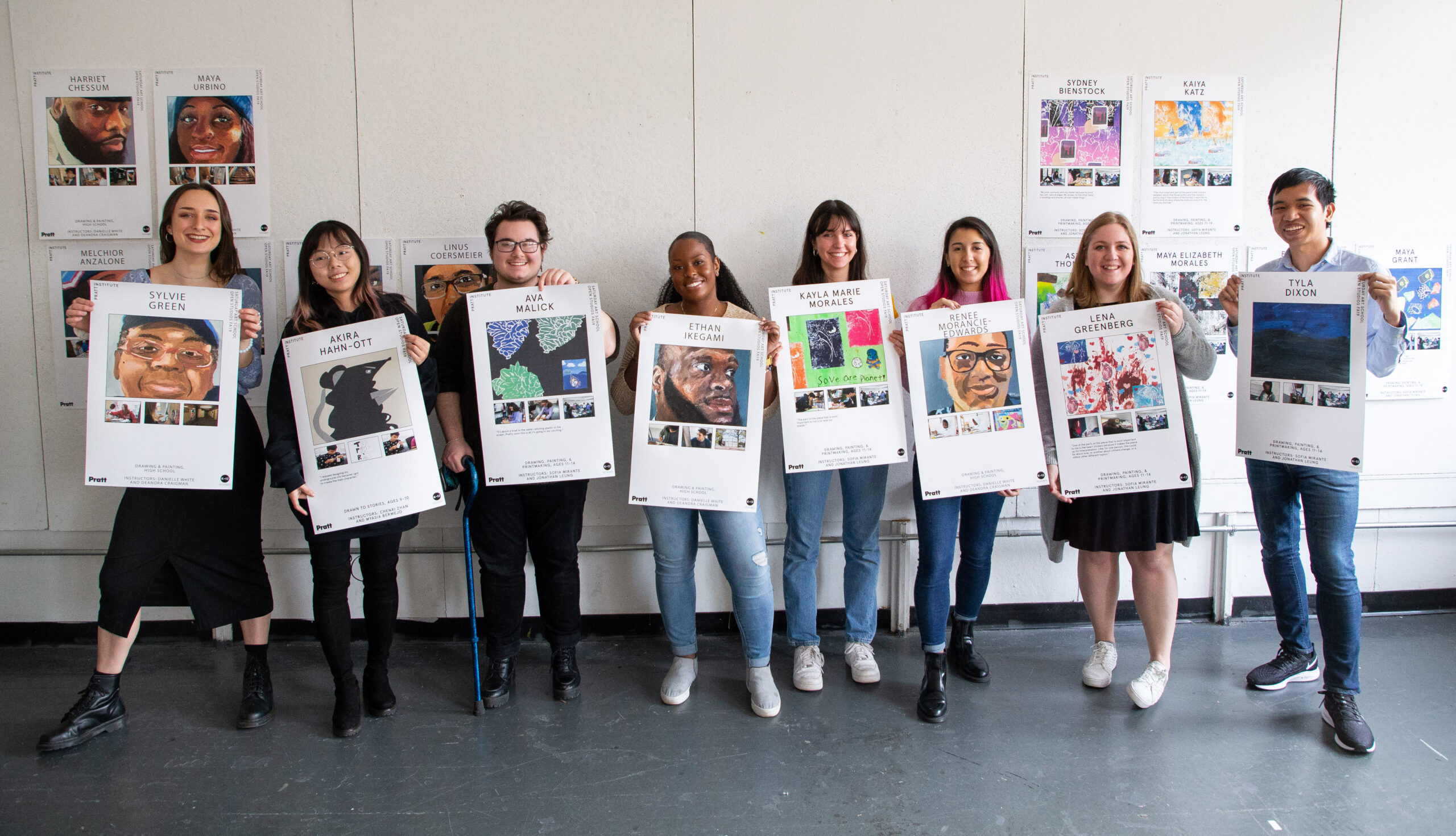 Students holding a poster of work produced by a child they taught in Saturday Art School.