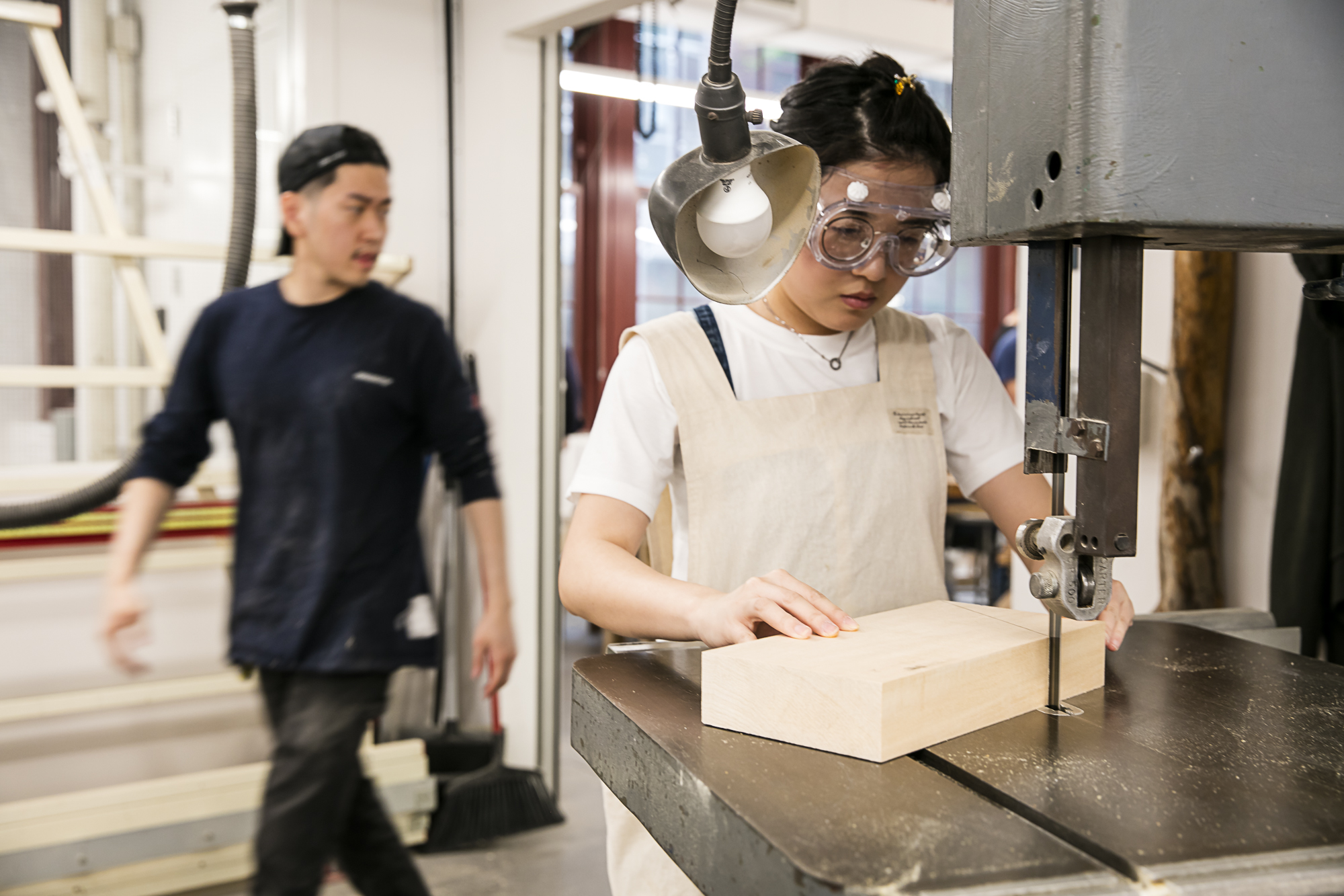 A student works at a saw in a shop.